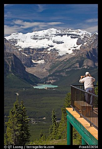 Man looking at Lake Louise through binoculars on observation platform. Banff National Park, Canadian Rockies, Alberta, Canada (color)