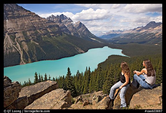 Tourists sitting on a rook overlooking Peyto Lake. Banff National Park, Canadian Rockies, Alberta, Canada