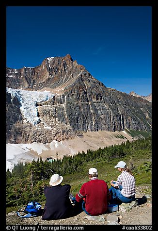 Hikers sitting in front of Mt Edith Cavell next to trail. Jasper National Park, Canadian Rockies, Alberta, Canada