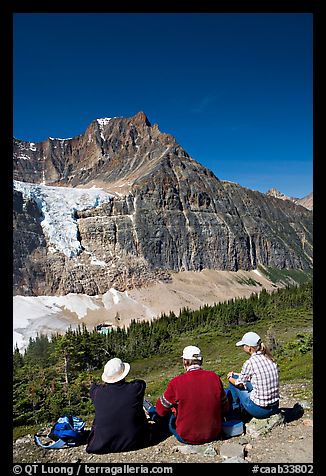 Hikers sitting in front of Mt Edith Cavell next to trail. Jasper National Park, Canadian Rockies, Alberta, Canada (color)