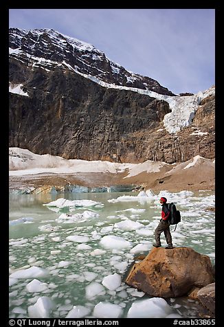 Hiker with backpack looking at iceberg-filed lake, glaciers, and mountain, Mt Edith Cavell. Jasper National Park, Canadian Rockies, Alberta, Canada