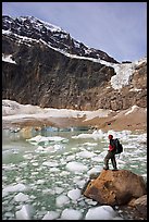 Hiker with backpack looking at iceberg-filed lake, glaciers, and mountain, Mt Edith Cavell. Jasper National Park, Canadian Rockies, Alberta, Canada ( color)