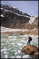 Hiker with backpack looking at iceberg-filed lake, glaciers, and mountain, Mt Edith Cavell. Jasper National Park, Canadian Rockies, Alberta, Canada