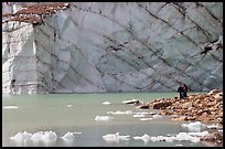 Hikers on the shore of Cavell Pond with high glacier wall behind. Jasper National Park, Canadian Rockies, Alberta, Canada (color)