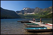 Dock and small boats, with tourists walking down, Cameron Lake. Waterton Lakes National Park, Alberta, Canada