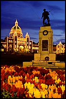 Flowers, memorial statue and illuminated parliament building at night. Victoria, British Columbia, Canada