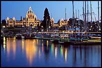 Boats in inner harbor with a trail of lights and parliament building lights. Victoria, British Columbia, Canada