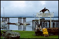 Backpacker sitting under the Transcanadian terminus sign, Tofino. Vancouver Island, British Columbia, Canada