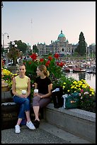 Women with shopping bags and coffee cups at the Inner Harbour, sunset. Victoria, British Columbia, Canada