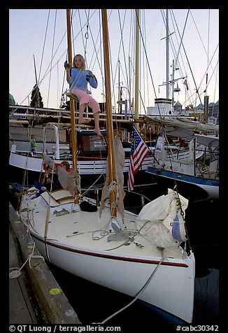 Girl swinging from the mast of a small sailboat, Inner Harbour. Victoria, British Columbia, Canada