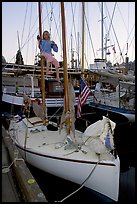 Girl swinging from the mast of a small sailboat, Inner Harbour. Victoria, British Columbia, Canada