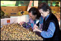 Two elderly women choosing tropical fruit. Vancouver, British Columbia, Canada (color)