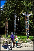 Family with bicycles looking at Totems, Stanley Park. Vancouver, British Columbia, Canada