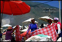 Bai women examining a piece of cloth at the Monday market. Shaping, Yunnan, China (color)