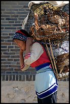 Woman carrying a load of chicken cages on forehead. Shaping, Yunnan, China