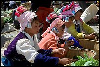 Bai women in tribal dress selling vegetables at the Monday market. Shaping, Yunnan, China