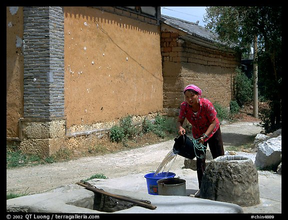 Bai woman fills up a water bucket at the well. Shaping, Yunnan, China (color)