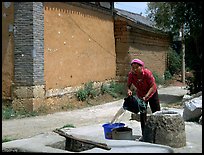 Bai woman fills up a water bucket at the well. Shaping, Yunnan, China