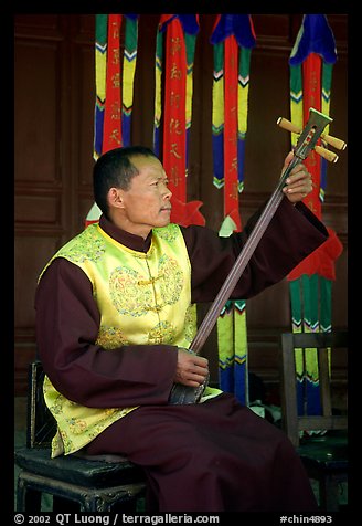 Musician playing a three-stringed traditional moon guitar. Baisha, Yunnan, China (color)