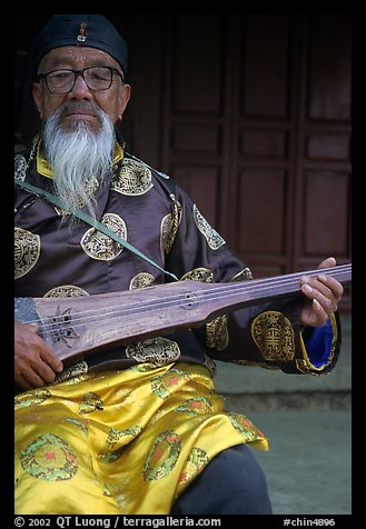 Elderly musician playing the a traditional guitar. Baisha, Yunnan, China