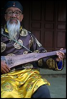 Elderly musician playing the a traditional guitar. Baisha, Yunnan, China