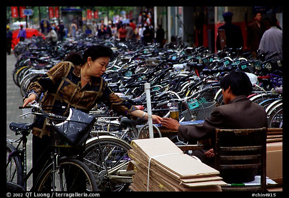 Woman checking out her bicycle at a bicycle lot. Kunming, Yunnan, China (color)