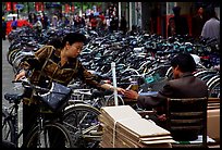 Woman checking out her bicycle at a bicycle lot. Kunming, Yunnan, China (color)