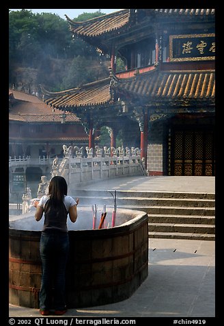 Woman offers incense in the central courtyard of Yantong Si. Kunming, Yunnan, China (color)