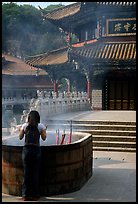 Woman offers incense in the central courtyard of Yantong Si. Kunming, Yunnan, China