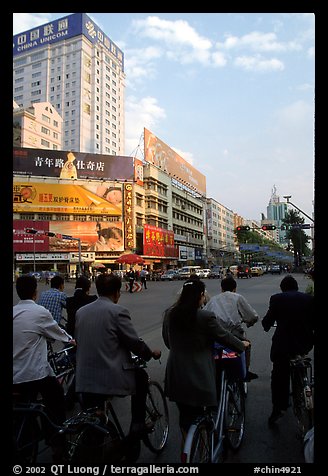 Bicyclists wait for the green light on a modern avenue. Kunming, Yunnan, China (color)