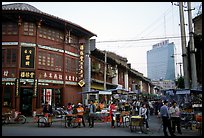 Old wooden buildings, with a high rise in the background. Kunming, Yunnan, China (color)