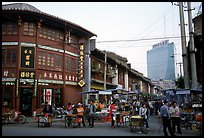 Old wooden buildings, with a high rise in the background. Kunming, Yunnan, China