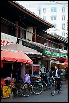 Man on bicycle in front of wooden buildings. Kunming, Yunnan, China