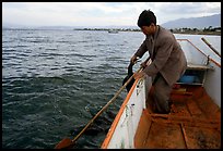 Cormorant fisherman catches one of his birds to retrieve the fish it caught. Dali, Yunnan, China