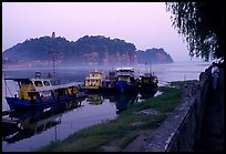 Boats along the river with cliffs in the background. Leshan, Sichuan, China (color)