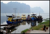 Boats along the river with misty cliffs in the background. Leshan, Sichuan, China