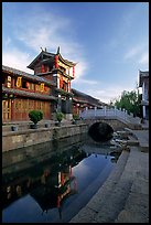 Kegong tower (memorial archway of imperial exam) reflected in canal, sunrise. Lijiang, Yunnan, China