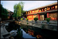 Buildings on Square street reflected in canal, sunrise. Lijiang, Yunnan, China