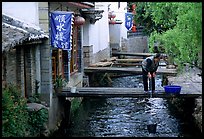 Woman fills up a water buck in the canal. Lijiang, Yunnan, China