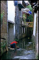 Woman washes clothes in the canal. Lijiang, Yunnan, China