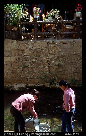 Women washing clothes in a canal. Lijiang, Yunnan, China