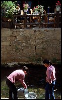 Women washing clothes in a canal. Lijiang, Yunnan, China