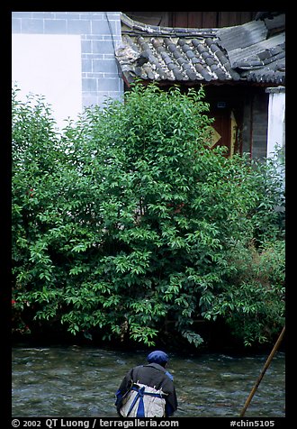 Naxi woman sitting next to a canal. Lijiang, Yunnan, China (color)