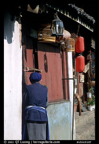 Naxi woman at the door of her wooden house. Lijiang, Yunnan, China