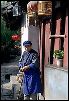 Naxi woman at the door of her wooden house. Lijiang, Yunnan, China