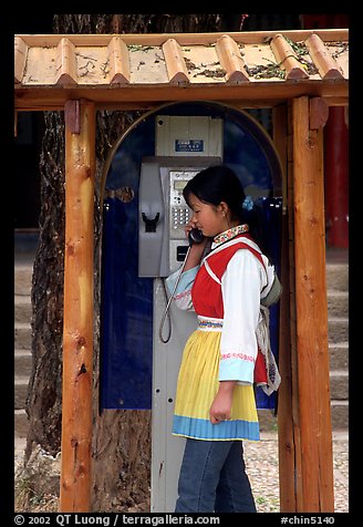 Woman in Naxi dress in a telephone booth. Lijiang, Yunnan, China (color)