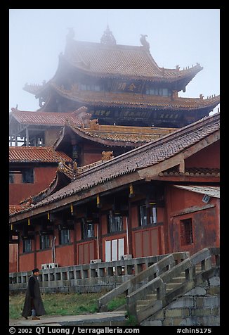 Monk beneath Jinding Si (Golden Summit) temple in the fog. Emei Shan, Sichuan, China (color)