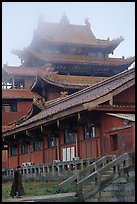 Monk beneath Jinding Si (Golden Summit) temple in the fog. Emei Shan, Sichuan, China (color)