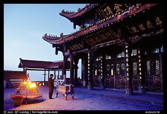 Pilgrim prays in the Jinding Si (Golden Summit) temple at dusk. Emei Shan, Sichuan, China (color)