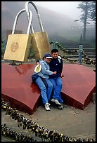 Lovers sit on top of two hearts surrounded by chain locks. Emei Shan, Sichuan, China (color)